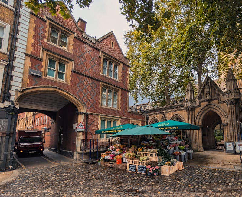 A vibrant flower stall located on a cobbled street near Whalebone Lane Marks Gate features an array of fresh floral arrangements, including pink roses, white lilies, and yellow chrysanthemums, display
