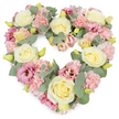 A generous heart-shaped wreath of pastel flowers is shown against a pristine white background, creating a serene and respectful image ideal for a funeral or memorial setting. The heart is completely filled with blooms, forming a smooth, continuous outline that symbolises unbroken love and remembrance. Cream and pale yellow roses feature prominently, their soft, spiralled petals opening in calm, rounded forms that convey grace and tenderness. Around and between them, numerous blush-pink carnations bring a delicate, feathery texture, their frilled edges giving the impression of gentle movement, like a whispered blessing. Deeper pink and mauve lisianthus flowers are scattered through the design, adding nuanced colour and a touch of quiet romance, each bloom slightly more open and relaxed than the structured roses. Cool, silvery eucalyptus leaves weave throughout the wreath, their rounded shapes and dusky green tones providing contrast and a soothing, natural rhythm, much like the peaceful streets and small green corners around Marks Gate. Small yellowish-green buds peek out from the flowers, subtle signs of new life and hope amid the softness of the pastels. The overall effect is lush and full, with each blossom nestled closely to the next, reflecting the careful hands and compassionate eye of an experienced florist. This heart-shaped tribute is especially suited to expressing condolences for services held in the Marks Gate area, offering a visual message of sympathy, comfort, and lasting affection when words alone may not be enough.